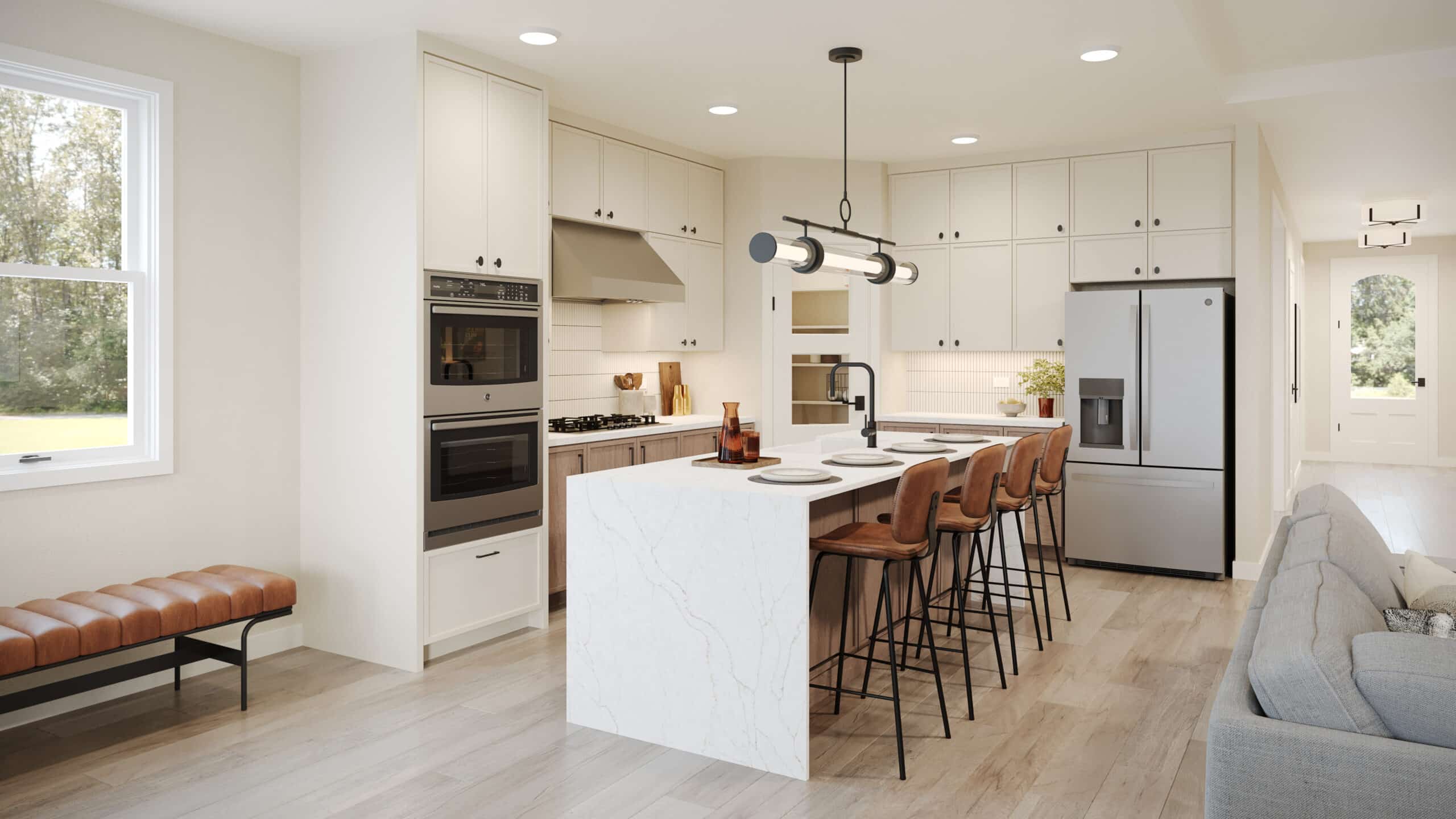 Bright modern kitchen with a white marble island, four leather bar stools, stainless steel double oven and refrigerator, and a gray sofa at right.