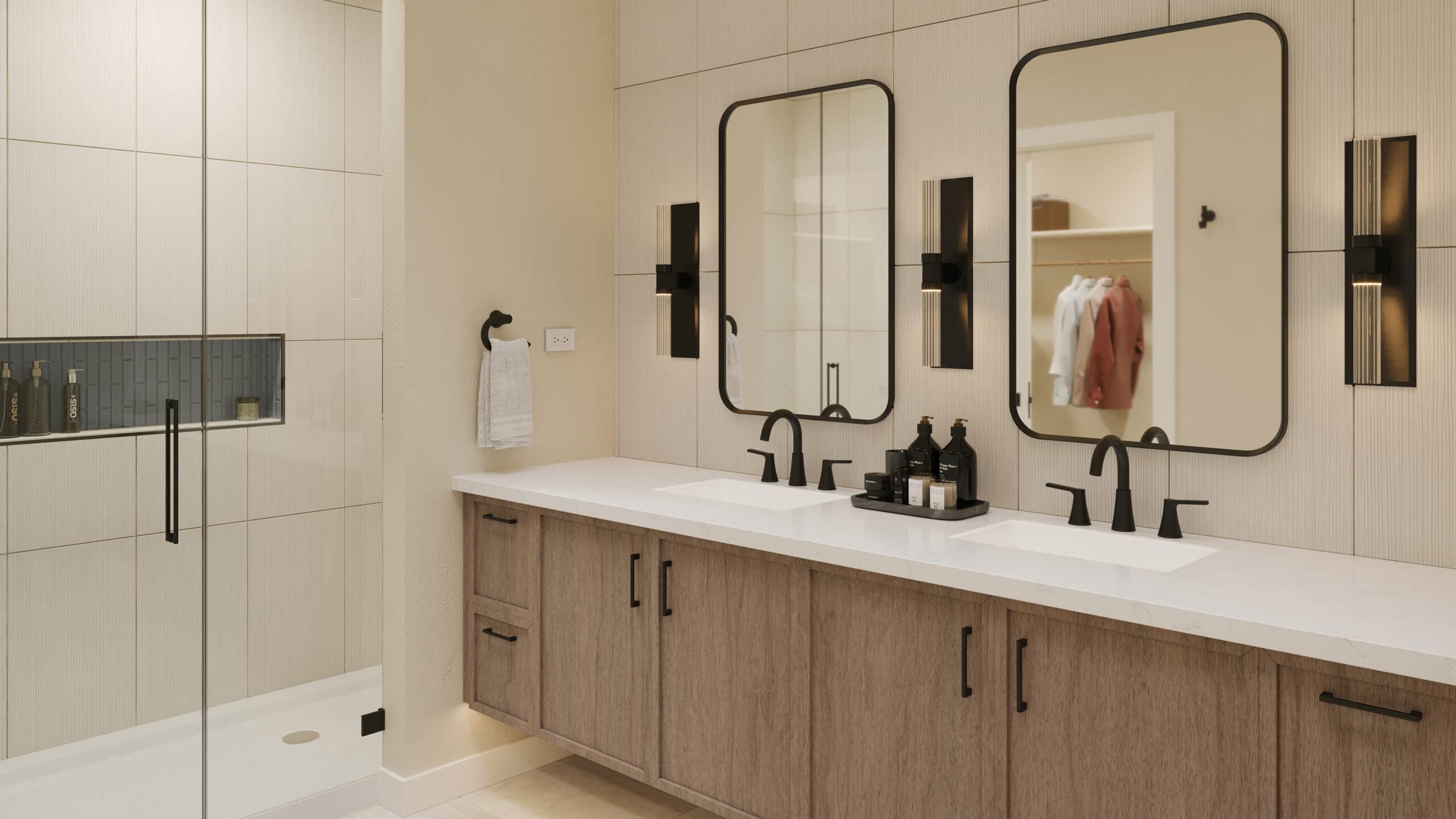 Modern double-sink bathroom vanity with white countertop, wood cabinets, two black-framed mirrors, matte black faucets and wall sconces, and a glass-enclosed shower with built-in niche.
