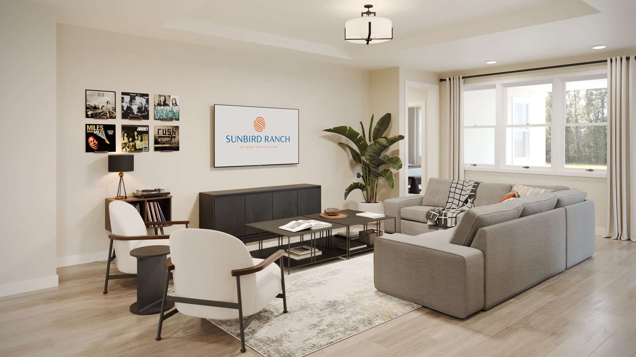 Bright modern living room with gray sectional sofa, two armchairs, coffee table, wall-mounted TV reading "Sunbird Ranch," and large window