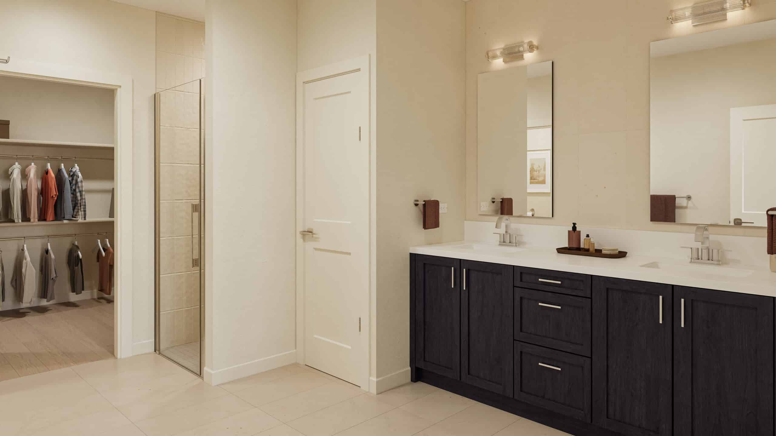 Spacious bathroom with a double vanity, large mirrors, tiled shower, and adjoining walk-in closet