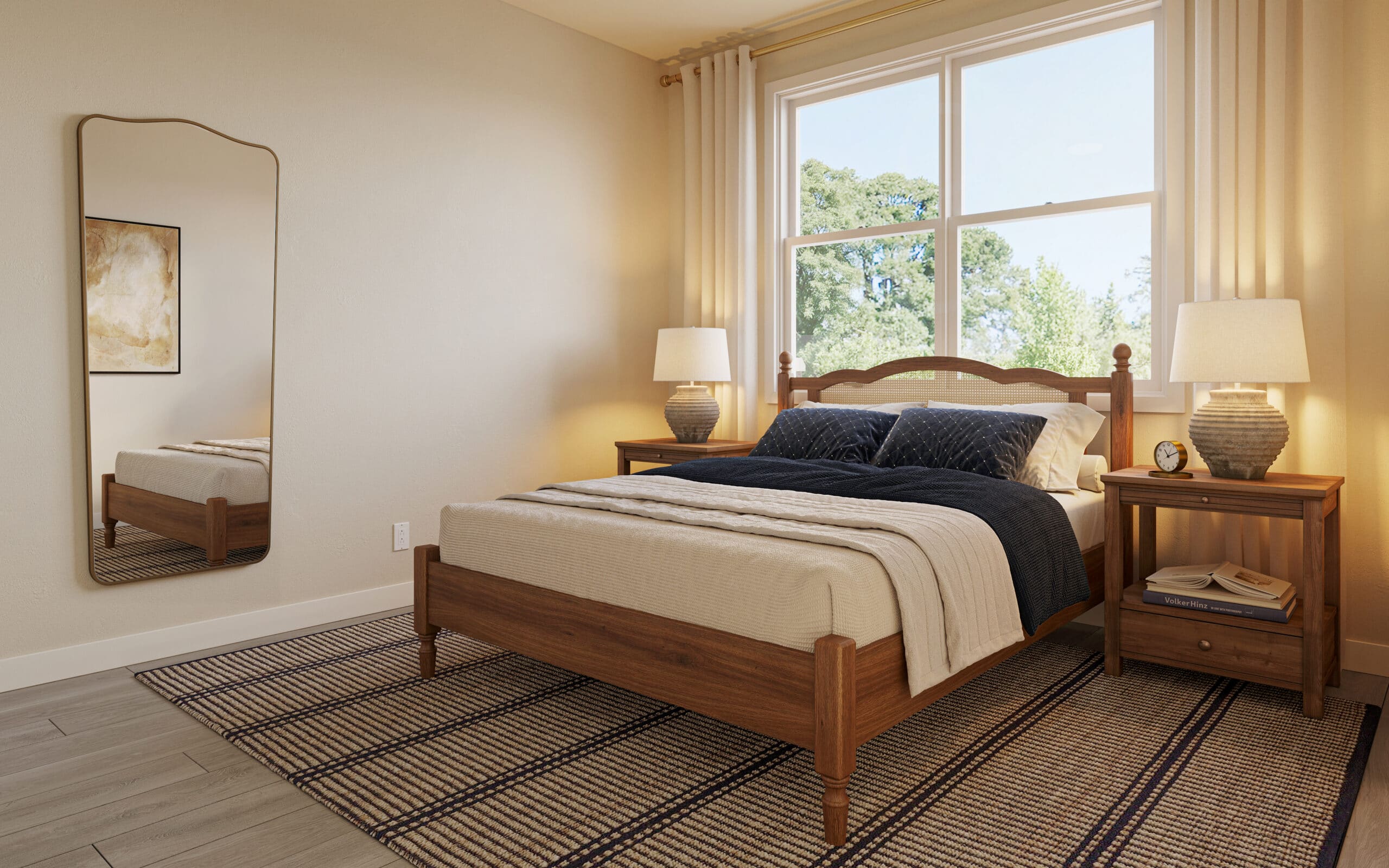 Bright bedroom with a wooden bed, navy and cream bedding, bedside tables and lamps, a large window, and wall mirror